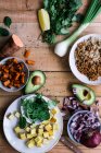 Von oben geschnittene Zwiebel und Avocado mit Süßkartoffeln und Gemüse im Prozess der Mahlzeitenzubereitung auf rustikalem Tisch — Stockfoto