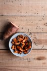 Top view of half of raw sweet potato and pieces of baked sweet potato in bowl on rustic wooden table — Stock Photo