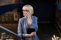 Блондинка бізнес-леді розмовляє на смартфоні — стокове фото