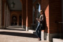 Businesswoman with tablet at wall — Stock Photo