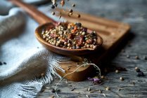 Dry mix of spices and dried berries in spoon on table — Stock Photo