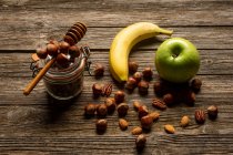 Apfel und Banane mit Nüssen auf Holztisch — Stockfoto