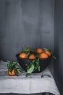 Оранжевые мандарины в керамической чаше на столе — стоковое фото