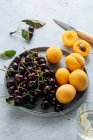 Плоский укладка вкусной вишни и желтых персиков подается на тарелке на белом фоне . — стоковое фото