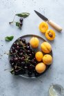 Плоский шар смачних вишневих і жовтих персиків, які подаються на тарілці на білому тлі . — стокове фото
