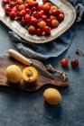 Flache Lage von köstlichen Kirschen und gelben Pfirsichen auf einem Teller auf rustikalem Hintergrund serviert — Stockfoto
