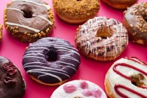 Різноманітність пончиків на рожевому фоні — стокове фото