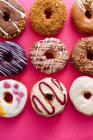 Variety of doughnuts on pink background — Stock Photo