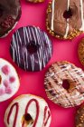 Разнообразие пончиков на розовом фоне — стоковое фото