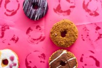 Різноманітність пончиків на рожевому фоні — стокове фото