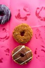 Variedad de rosquillas sobre fondo rosa - foto de stock