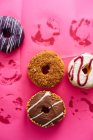 Variedad de rosquillas sobre fondo rosa - foto de stock