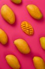 Poser à plat mangue fruits tranchés en demi-cubes dans un fond de carton rose coloré — Photo de stock
