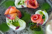 Rolos de salmão com cebola e ervas servidas em prato rústico na mesa de madeira — Fotografia de Stock
