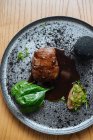 Vista dall'alto di deliziosa bistecca di carne gourmet con salsa ed erbe servite su piatto d'argento in metallo su sfondo di legno — Foto stock