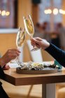 Unbekanntes Paar mit Sektgläsern probiert köstliche Austern mit Zitrone und Kräutern im Restaurant — Stockfoto