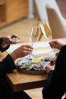 Casal irreconhecível com copos de champanhe experimentando deliciosas ostras com limão e ervas no restaurante — Fotografia de Stock