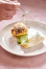 Persona irriconoscibile con cucchiaio che aggiunge salsa di panna a gustoso piatto di pesce con erba nel ristorante — Foto stock