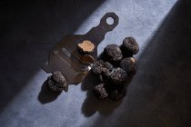 De cima cacho de trufas pretas caras colocadas perto de barbeador de metal na superfície de gesso cinza — Fotografia de Stock