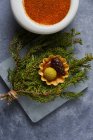 Top view of bunch of fresh conifer twigs with pickled cone and boiled egg yolk placed on scales near bowl with paprika — Stock Photo
