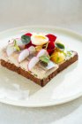 Delicioso sándwich de pescado con verduras frescas y huevos de codorniz hervidos colocados en el plato en la cafetería - foto de stock