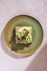 Сверху вкусный сэндвич с тунцом с ломтиками свежего авокадо на тарелке в кафетерии — стоковое фото