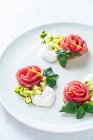 Rotoli di salmone con cipolla ed erbe serviti su un piatto di ceramica bianca su sfondo bianco — Foto stock