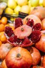 Granada fresca linda colocada en un montón de frutas en el puesto en la tienda de comestibles - foto de stock