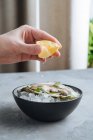 Personne cultivée méconnaissable pressant du citron sur de délicieuses huîtres sur du glaçon dans un bol au restaurant — Photo de stock