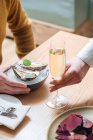 Unrecognizable cropped person with glasses of champagne trying delicious oysters with lemon and herbs in restaurant — Stock Photo