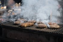 De dessus de escalope de cuisson avec de la fumée sur le gril dans la stalle du marché — Photo de stock
