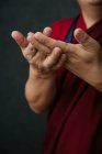 Primo piano delle mani del raccolto pregando monaco tibetano in tradizionale veste rossa con mudra gesto simbolico mani — Foto stock