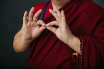 Close-up de mãos de colheita orando monge tibetano em roupão vermelho tradicional com mudra gesto mãos simbólicas — Fotografia de Stock
