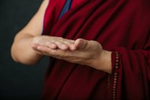 Nahaufnahme der Hände eines betenden tibetischen Mönchs in traditioneller roter Robe mit symbolischer Handbewegung — Stockfoto