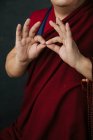 Gros plan des mains de moine tibétain priant en robe rouge traditionnelle avec geste des mains symboliques mudra — Photo de stock