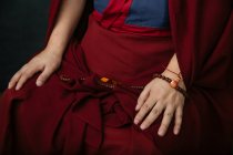 Seitenansicht der Ernte buddhistischer Mönch in traditioneller roter Kleidung hält Gebetsperlen in der Hand — Stockfoto