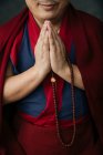 Vista laterale di coltura monaco buddista in abiti rossi tradizionali tenendo perline di preghiera in mano — Foto stock
