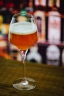Cerveja em vinho com espuma em vidro no balcão de madeira em bar no fundo borrão — Fotografia de Stock