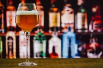 Bier im Weinglas mit Schaumstoff im Glas auf Holztheke in Bar auf unscharfem Hintergrund — Stockfoto