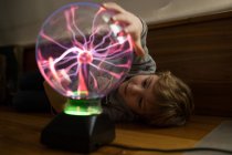 Boy looking at mysterious glass lightening lamp on table — Stock Photo