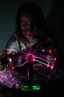 Charmed girl touches glowing ball with hand in dark — Stock Photo