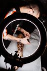 Unrecognizable man tattooer using smartphone to take picture of tattoo on leg of crop customer for portfolio in contemporary studio — Stock Photo