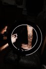 Невпізнаваний татуювання людини за допомогою смартфона, щоб сфотографувати татуювання на нозі клієнта врожаю для портфоліо в сучасній студії — стокове фото