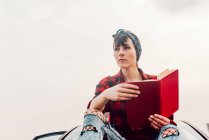 Nachdenkliche lässige Frau mit Buch am Strand — Stockfoto