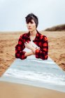 Самотня вдумлива жінка з великим дзеркалом, що стоїть на пляжі — стокове фото