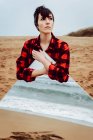 Самотня вдумлива жінка з великим дзеркалом, що стоїть на пляжі — стокове фото