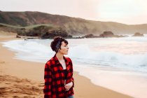 Женщина, стоящая на мокром песке на пляже — стоковое фото