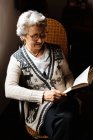 Mujer mayor leyendo por ventana con entusiasmo - foto de stock