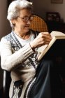 Donna anziana che legge alla finestra con entusiasmo — Foto stock