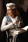 Mujer mayor leyendo por ventana con entusiasmo - foto de stock